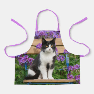 Tuxedo cat sitting on a garden chair with flowers apron
