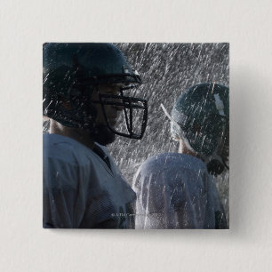 Two American football players in rain, side view Button