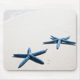 Two blue starfish at water's edge on tropical mouse pad