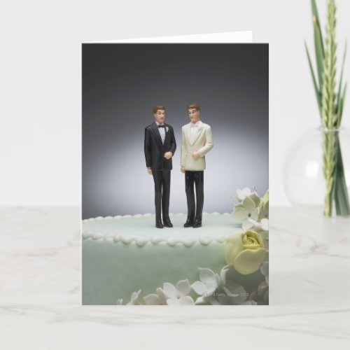Two groom figurines on top of wedding cake card
