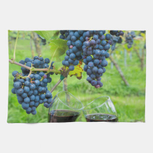 Two hands toasting with red wine near blue grapes kitchen towel