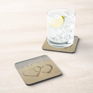 Two overlying hearts drawn on the beach with coaster