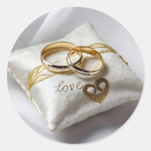 Two wedding rings on a white pillow classic round sticker