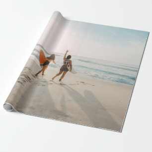 Two women walking towards the ocean carrying surfb wrapping paper
