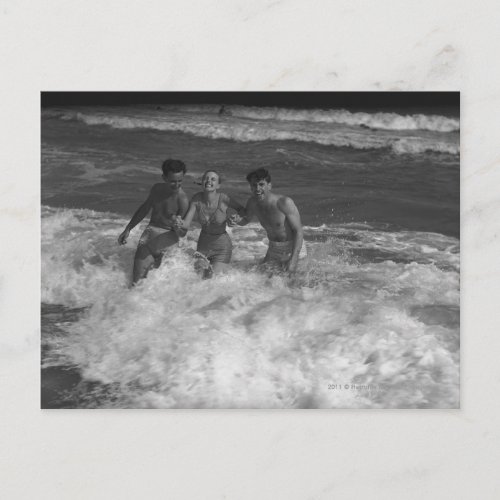Two young men and woman playing in wave BW Postcard