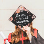 Unwritten | Custom Class Year Graduation Cap Topper<br><div class="desc">Cute grad cap topper features the quote "the rest is still unwritten" in white calligraphy lettering on a black background adorned with blush pink and peach flowers. Personalize with your class year.</div>