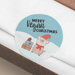 Vegan Christmas with nice piglet and presents Classic Round Sticker<br><div class="desc">This Vegan Christmas sticker features a nice cartoon piglet with a red hat and scarf and some colorful presents, on a snowy background. The black text says "Merry Vegan Christmas". If you need help, further customization, or other matching items, please feel free to contact me. (See matching vegan items in...</div>