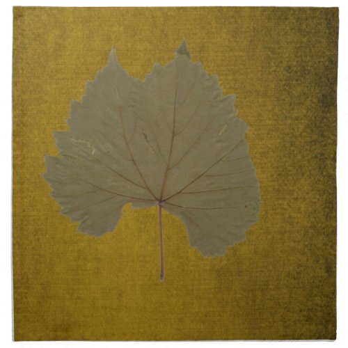 Vintage dusty grey dry leaf on yellowish brown napkin