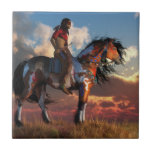 Warrior and War Horse Tile<br><div class="desc">On endless grassy plains, an American Indian warrior sits on the back of his trusted war horse and watches as the sun sets in a sky filled with puffy clouds. The Native American man carries a tomahawk and wears red and black war paint. The mustang has a dun and white...</div>