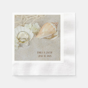wedding rings and seashells in sand napkins