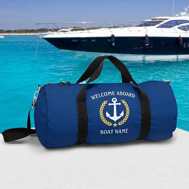 A blue duffel bag with a nautical design sits in front of a blue sea background with a large boat.