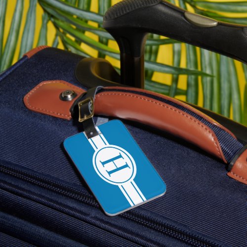 White band and oval shield with monogram on blue luggage tag