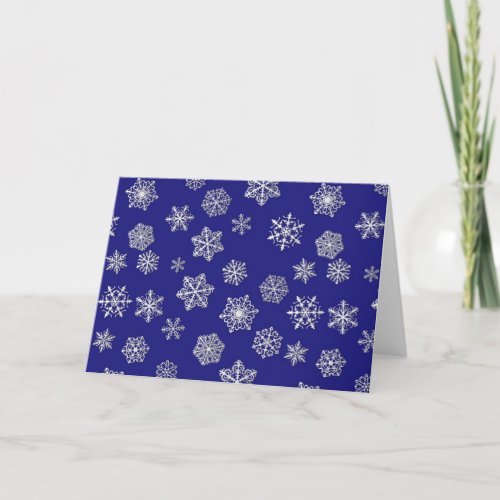 White snowflakes against deep cobalt blue holiday card