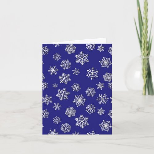 White snowflakes against deep cobalt blue holiday card