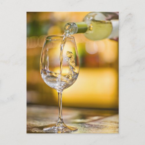 White wine is poured from bottle in restaurant postcard