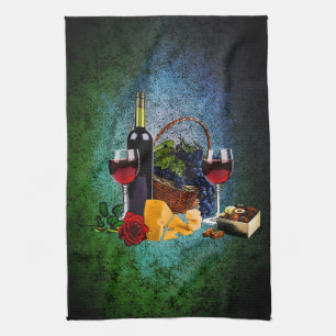 Wine glasses, bottle, grapes, cheese, chocolates kitchen towel
