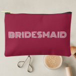 Wine Red Modern Typography Bridesmaid Accessory Pouch<br><div class="desc">Solid wine red color,  small style,  zippered cosmetic bag for your wedding bridesmaid that features the word,  BRIDESMAID in large,  modern typography on one side of bag. Perfect as a travel accessory pouch to hold makeup,  perfume,  and jewelry. You may personalize by adding bridesmaid name if desired to pouch.</div>