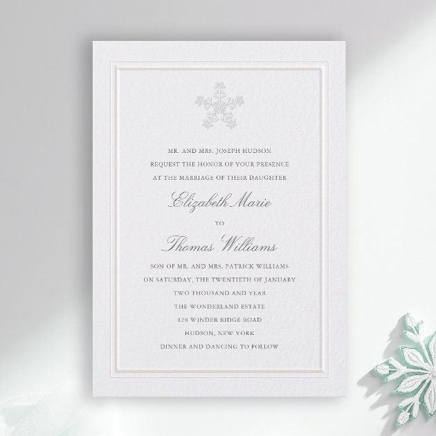 Modern classic winter wedding invitation with ivory watercolour background and an elegant snowflake crest resembling lace