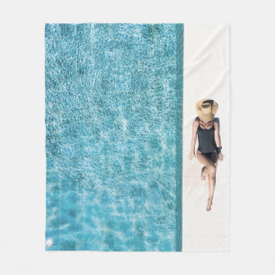 Woman in black bikini bottom and white sun hat sta fleece blanket
