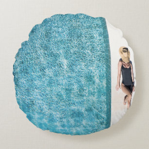 Woman in black bikini bottom and white sun hat sta round pillow