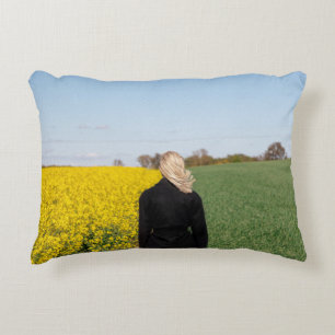 Woman in black coat standing on green grass field accent pillow