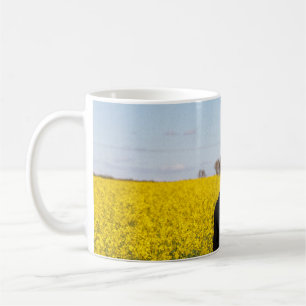 Woman in black coat standing on green grass field  coffee mug