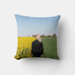 Woman in black coat standing on green grass field throw pillow