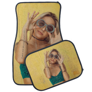 Woman in blue bralette holding sunglasses putting car floor mat