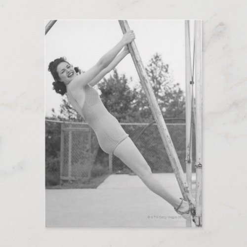 Woman in swimsuit hanging from wooden postcard