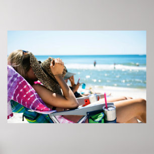 Woman lying on sun lounger covering her face with poster