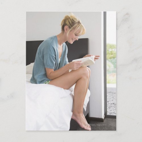 Woman reading a book on the bed postcard