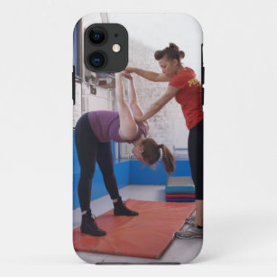Woman stretching with trainer in gym iPhone 11 case