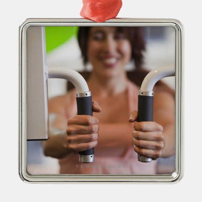 Woman using exercise machine in gym metal ornament (Front)