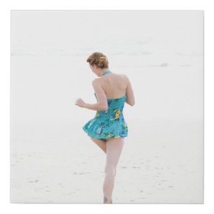 Woman walking on shore near beach faux canvas print