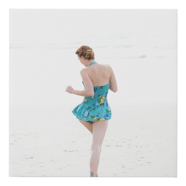 Woman walking on shore near beach faux canvas print (Front)
