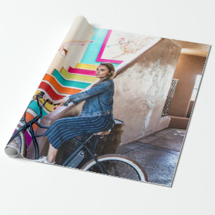 Woman wearing blue denim jacket and shorts riding wrapping paper