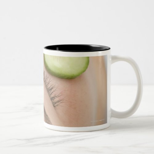 Woman with slices of fresh cucumber on her face Two_Tone coffee mug