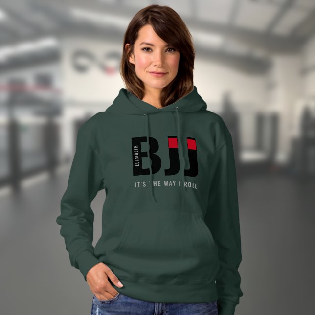 Woman's BJJ Personalized Hoodie (Dark green woman's BJJ hoodie worn by a female model in a gym.)