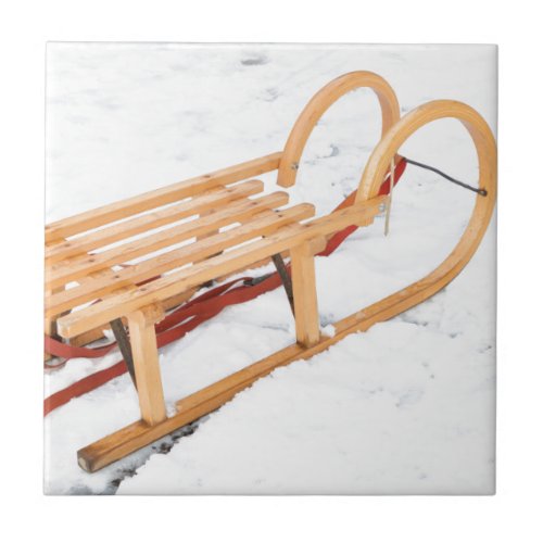 Wooden children sled in winter snow tile