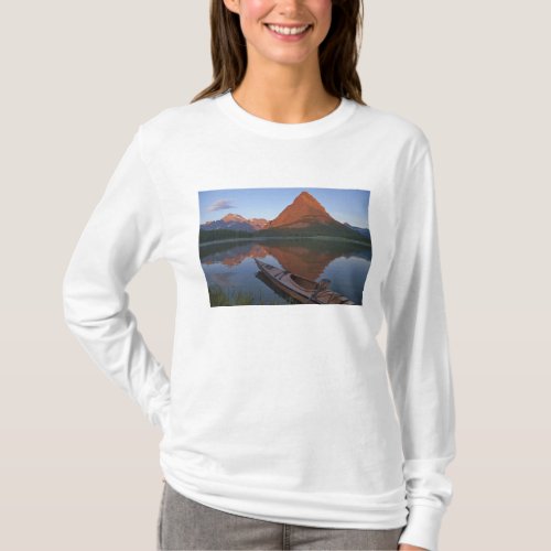 Wooden kayak in Swiftcurrent Lake at sunrise in T_Shirt