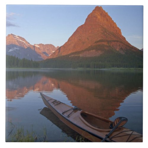 Wooden kayak in Swiftcurrent Lake at sunrise in Tile