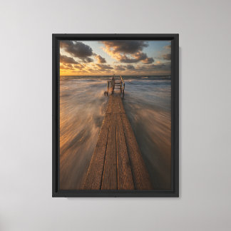 Wooden Pier Leading into Ocean Waves at Sunset Canvas Print