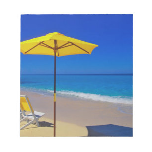 Yellow beach umbrella and chairs on pristine notepad
