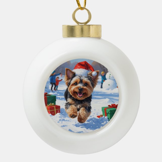 Yorkipoo Running in Snow with Christmas Hat Ceramic Ball Christmas Ornament (Front)