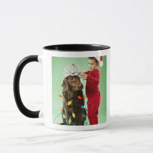 Young boy wrapping Christmas lights around a dog Mug
