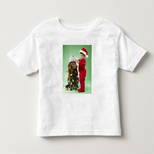 Young boy wrapping Christmas lights around a dog Toddler T_shirt