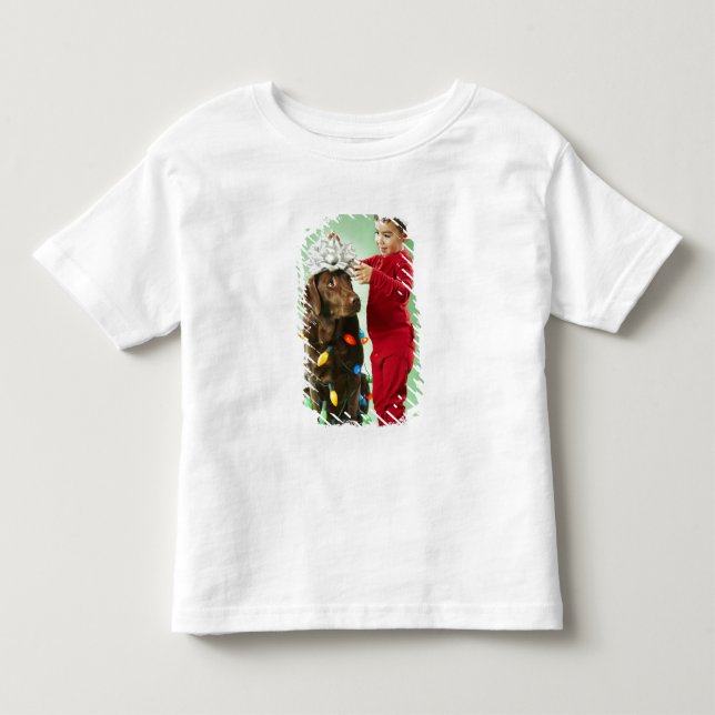 Young boy wrapping Christmas lights around a dog Toddler T-shirt (Front)