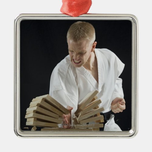 Young man breaking boards with karate chop on metal ornament