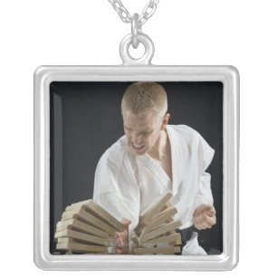 Young man breaking boards with karate chop on silver plated necklace
