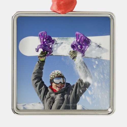 Young man holding his snowboard above his head metal ornament